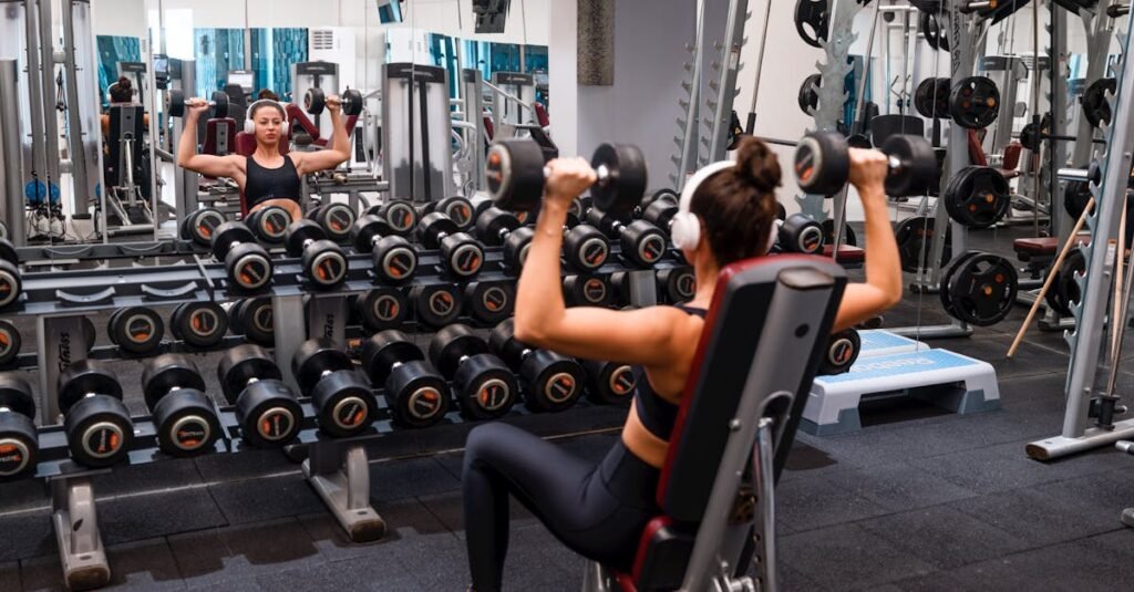 Woman exercising in the gym lifting dumbbells with headphones on for a strength-building workout.