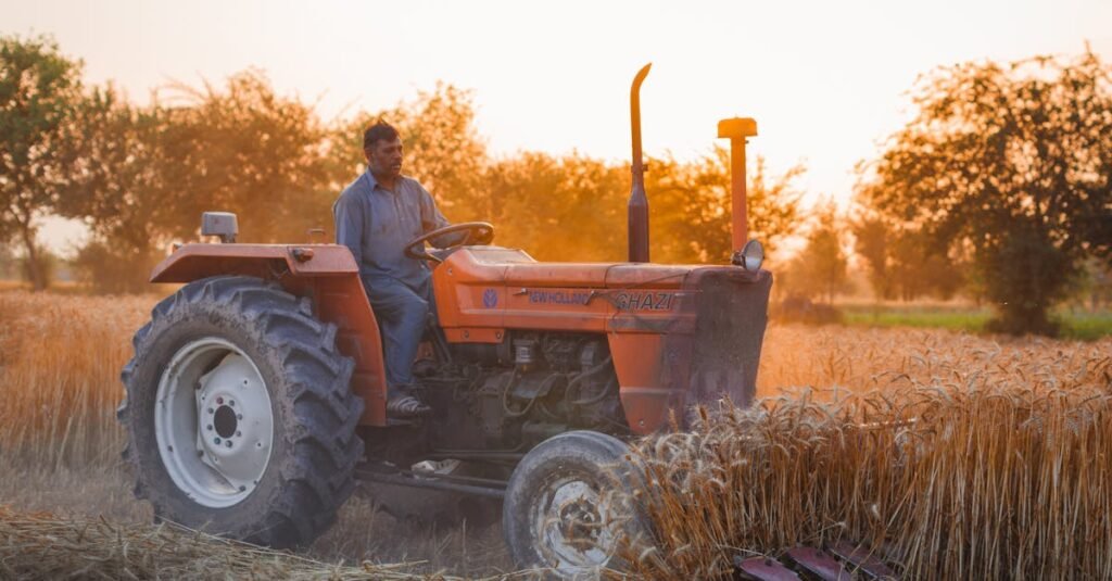 A farmer drives a tractor through a golden wheat field at sunset, showcasing traditional agriculture.